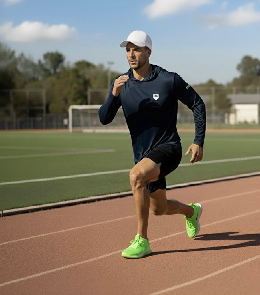 Male runner on a track wearing LIV.U Launch.KIT Performance long sleeve shirt, white cap, neon green sneakers.